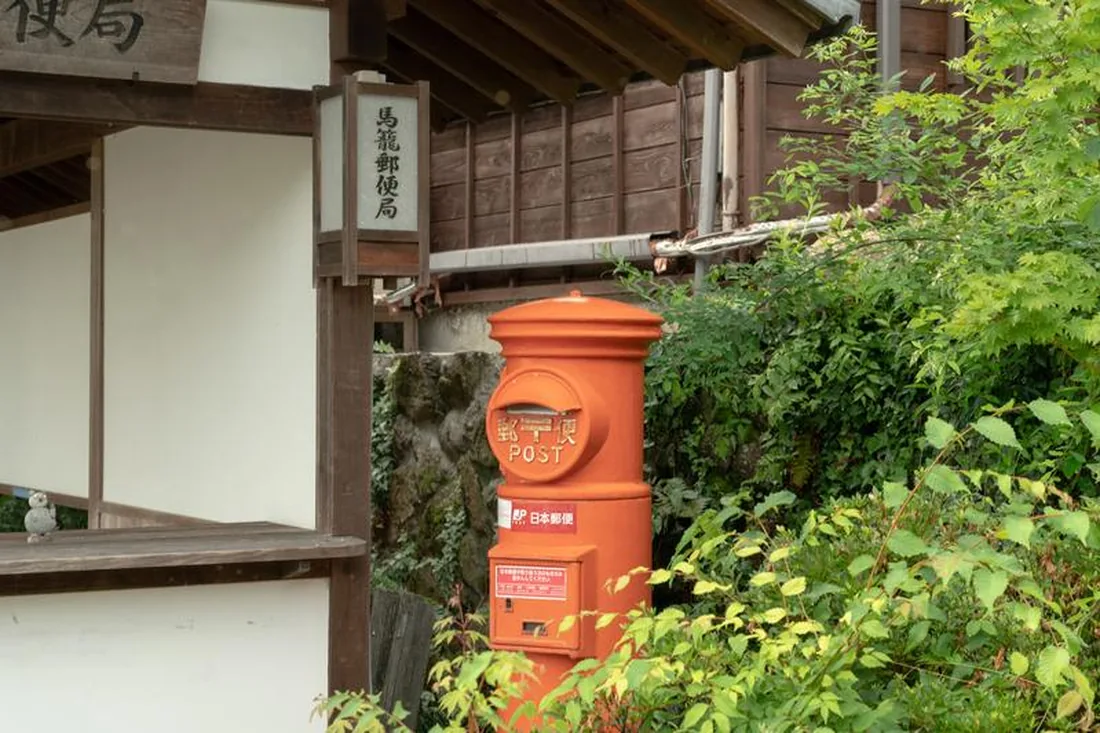 赤い丸型郵便ポストのある町並み